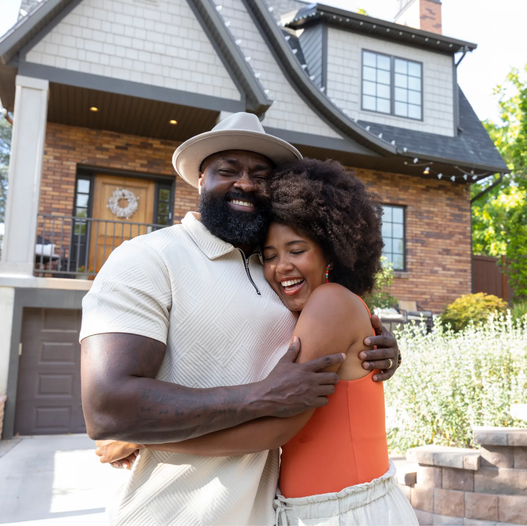 Middle-aged African American couple standing proudly in front of their brick home, ready to unlock equity with Cedar's cash-out solution
