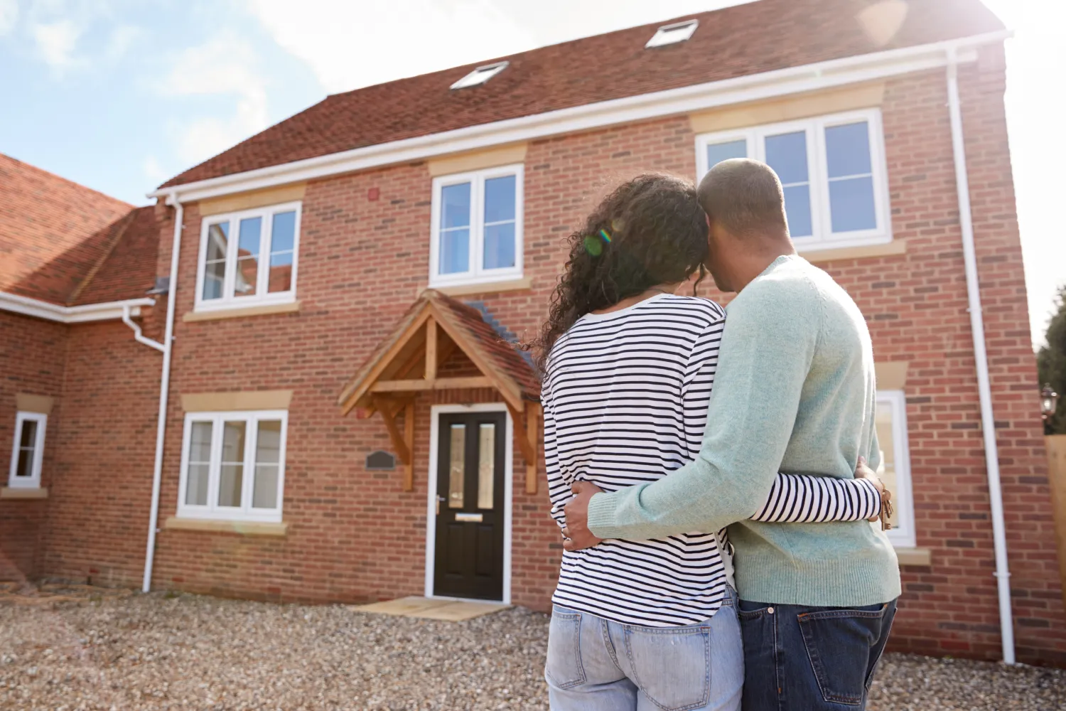 Couple standing outside their new home discussing Cedar's leasehold homeownership options